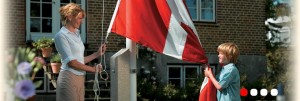 Mor og dreng står ved flagstang og hejser flaget sammen.